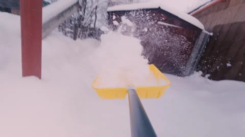 A guy clears a path from the snow with a large shovel to access the garage door. Stock Footage 325717300