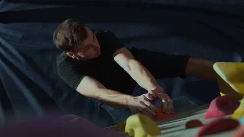 The guy climbs the artificial wall of the climbing wall inside the room Stock Footage 241067955