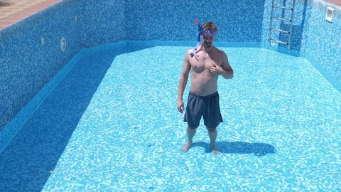 Guy climbs into an empty swimming pool with a snorkelling mask Stock Footage 90568676