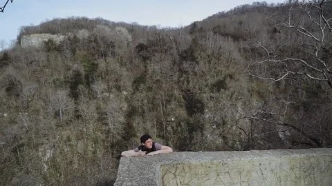 A guy climbs up the mountain, trying to take a selfie in a dangerous place but 库存影片 113671745
