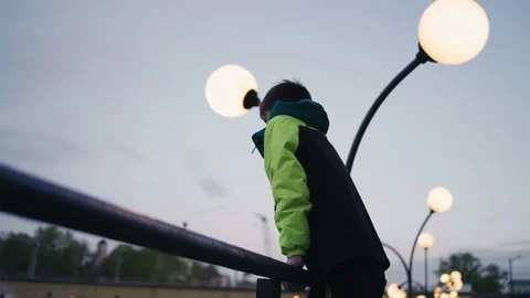 The guy climbs on the railing and looks towards the evening city Stock Footage 154126972