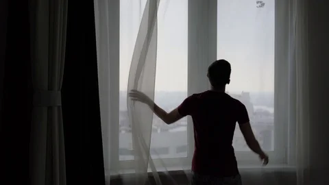Guy closes the tulle curtains on the window 库存影片 87708705