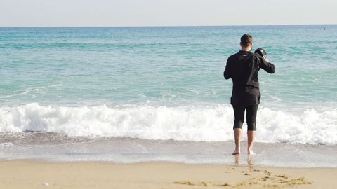 A guy in clothes stands on the shore of a cold and wavy sea in Barcelona Stock Footage 101269323