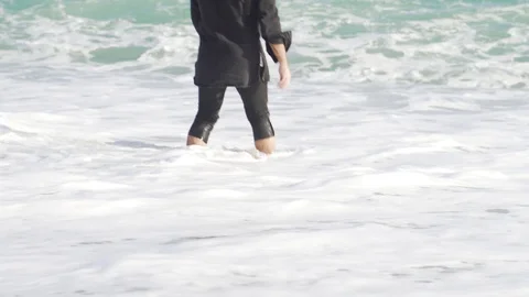 A guy in clothes stands on the shore of a cold and wavy sea in Barcelona Stock Footage 101269436