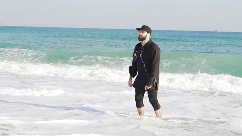 A guy in clothes stands on the shore of a cold and wavy sea in Barcelona Stock Footage 101269841