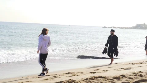 A guy in clothes walking on the shore of a cold and wavy sea in Barcelona Stock Footage 101269597