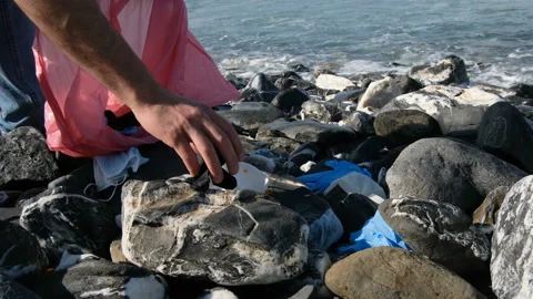 Guy collect Medical waste on sea shore,masks,plastic glove,coronavirus pollution Stock Footage