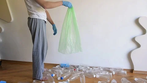 The guy collects and sorts plastic empty bottles into a large plastic bag. Stock Footage 129506302