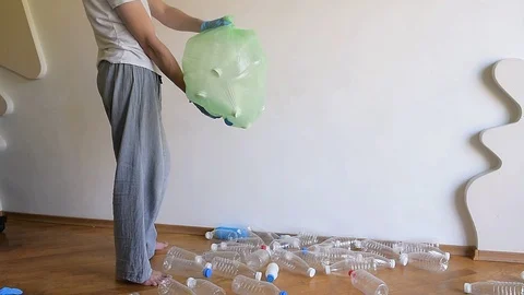The guy collects and sorts plastic empty bottles into a large plastic bag. Stock Footage 129506328