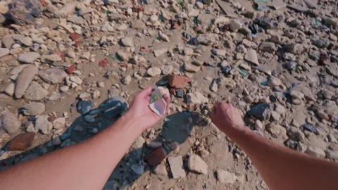 The guy collects broken glass on the beach by the sea so as not to cut himself. Video stock 339536445