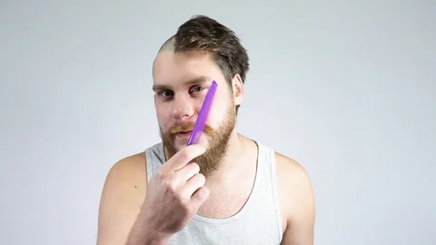The guy combing his beard with a comb.Half shaved hair on his head. Stock Footage 122216278