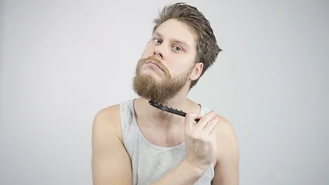 The guy combing his thick beard looking in the mirror 動画素材 121688139