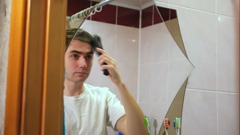 Guy combs his hair in the bathroom in front of the mirror, hair care Stock Footage 264887974