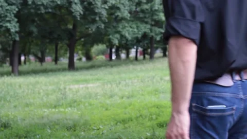 The guy comes to the bench, pulls out a smartphone from the back pocket of jeans Stock Footage 135238125