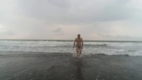 The guy comes out of the ocean on the beach on the island Stock Footage 105669724