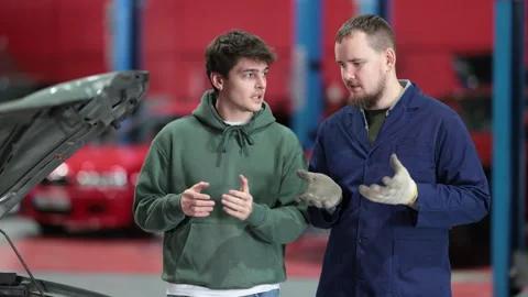 Guy communicates with a qualified mechanic about car maintenance and tire Stock Footage 341380283