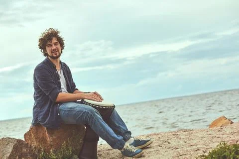 Guy is composing music on the seashore Stock Photos