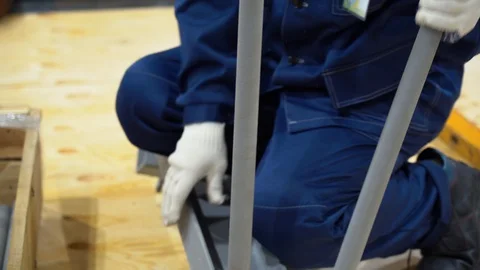 Guy connects gray pipes to main structure on wooden floor in workshop outdoor Stock Footage 126355663