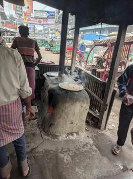 A guy cooking with burning fire on a clay farness Stock Photos