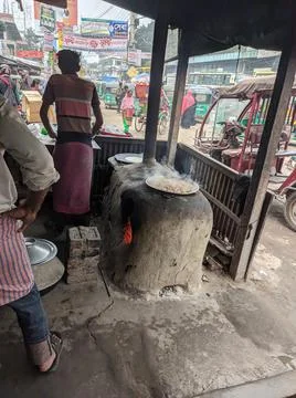 A guy cooking with burning fire on a clay farness Stock Photos