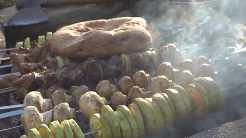 Guy cooks barbecue on a fire, vegetables, mushrooms and meat fries, pita bread Video stock 129459755