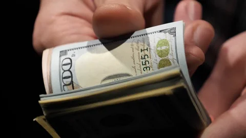 Guy counts dollars in a bundle close-up in slow motion. Video stock 129786339