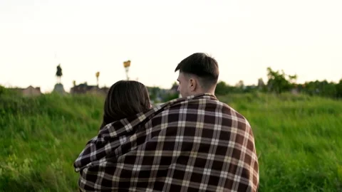 The guy covers his girlfriend with a blanket during a walk in the open air. Stockbeeldmateriaal 162195178
