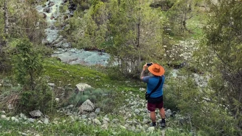 A guy in a cowboy hat is photographing a mountain river Stock-Footage 316879656