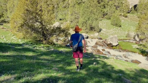 A guy in a cowboy hat walks along a stormy mountain river Video stock 316879644