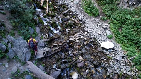 The guy crosses a mountain river on rocks. Stock Footage 160680715