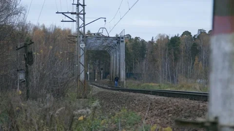 A guy is crossing railroad bridge over water in a countryside in Russia Stock Footage 150433384