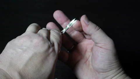 The guy cuts his own long nails on the fingers of his right hand with metal Video stock 143143302