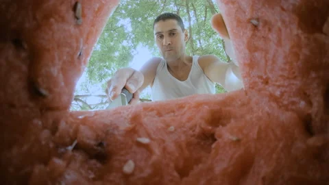 The guy cuts off a piece of watermelon with a knife and immediately eats it. Stock Footage 159154492