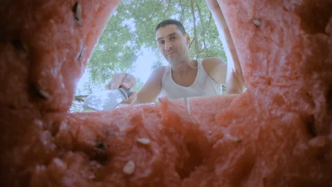 The guy cuts off a piece of watermelon with a knife and immediately eats it. Stock Footage 159154730