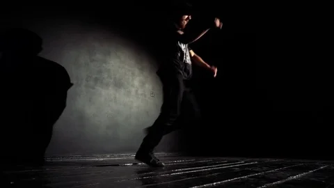 Guy dances a break dance in the dark on the floor dark hall Stock Footage 82585218
