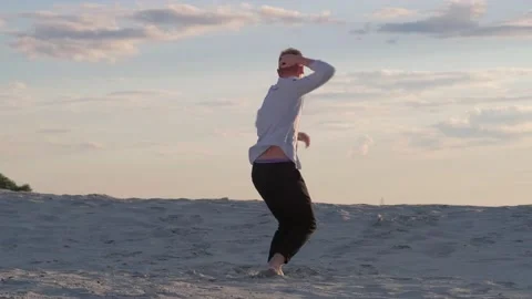 Guy dancing contemporary choreography on the sand at sunset. Slow motion Stock Footage 135611582