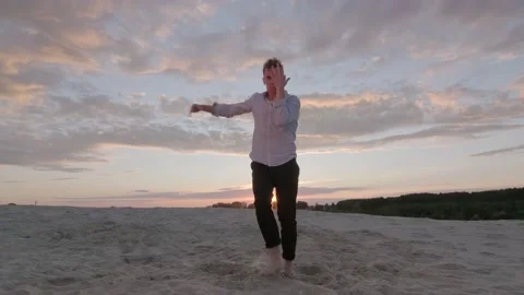 Guy dancing freestyle dance on the sand at sunset. Slow motion. Gimbal shot Stock Footage 135610693