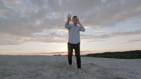 Guy dancing freestyle dance on the sand at sunset. Slow motion. Gimbal shot Stock Footage 135610756