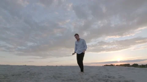 Guy dancing freestyle dance on the sand at sunset. Slow motion. Gimbal shot Stock Footage 135610758