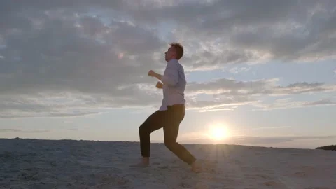 Guy dancing freestyle dance on the sand at sunset. Slow motion Stock Footage 135611361