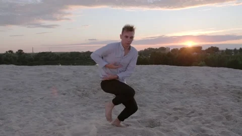 Guy dancing freestyle dance on the sand at sunset. Slow motion Stock Footage 135611446