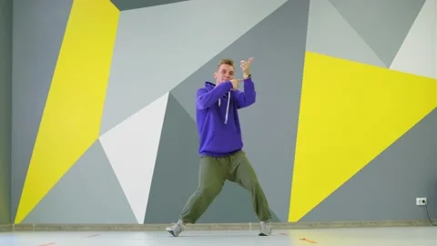 Guy dancing hip hop in studio in front of the wall with bright geometric pattern Stock Footage 139757387