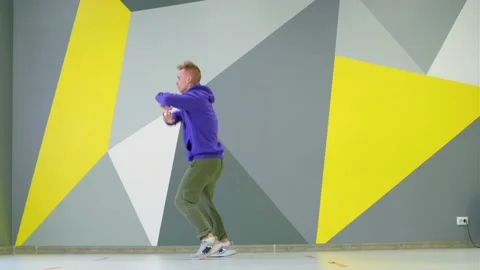 Guy dancing hip hop in studio in front of the wall with bright geometric pattern Stock Footage 139757410