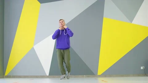 Guy dancing hip hop in studio in front of the wall with bright geometric pattern Stock Footage 139757518