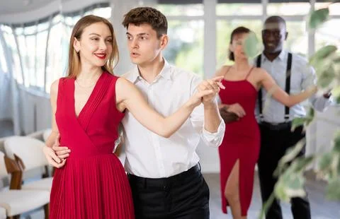 Guy dancing merengue with female partner in red in dance class Stock Photos