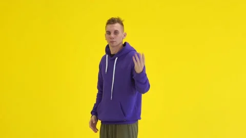 Guy dancing modern dance in the studio against the background of a yellow wall Stock Footage 142819973