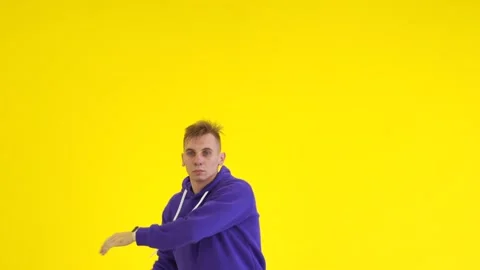 Guy dancing modern dance in the studio against the background of a yellow wall Stock Footage 142820232
