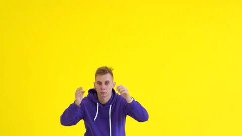 Guy dancing modern dance in the studio against the background of a yellow wall Stock Footage 142820264