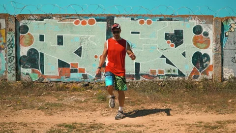 A guy dancing a shuffle against the backdrop of a painted light green wall Stock Footage 160893683