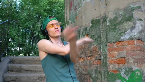 Guy is dancing tectonics in headphones and yellow glasses. Clouse up. 動画素材 122434333